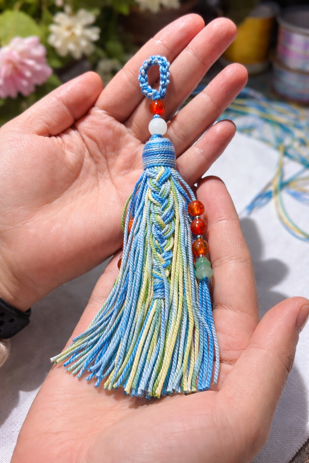 Beaded tassel pendant resting on book, natural light detail