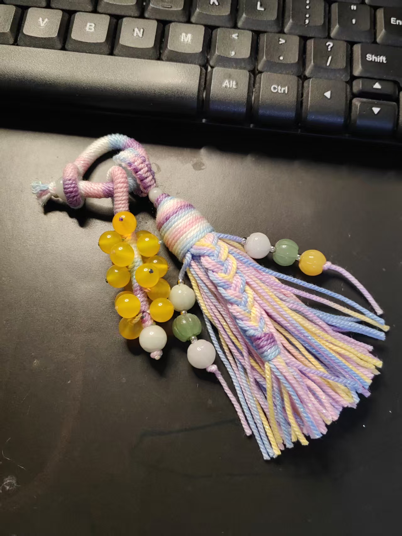 handwoven tassel pendant with hand twisted cotton cord and natural beads on dark background