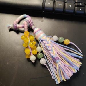 handwoven tassel pendant with hand twisted cotton cord and natural beads on dark background