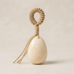 Handheld ivory nut fidget charm in an irregular egg shape with a premium beige hand-knotted loop cord, shown as a pocket anxiety relief item.